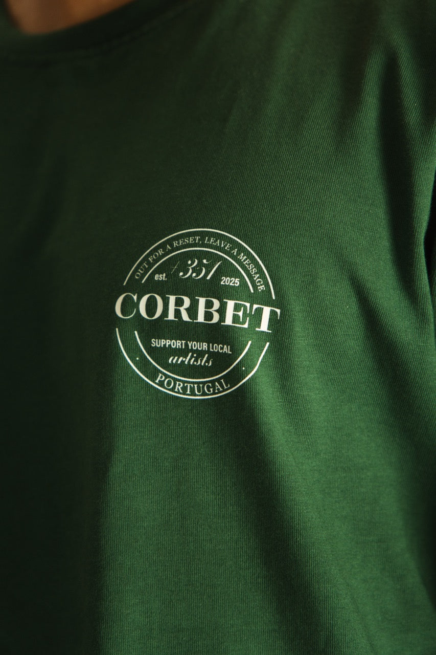 Green t-shirt with a white logo and text on a dark background