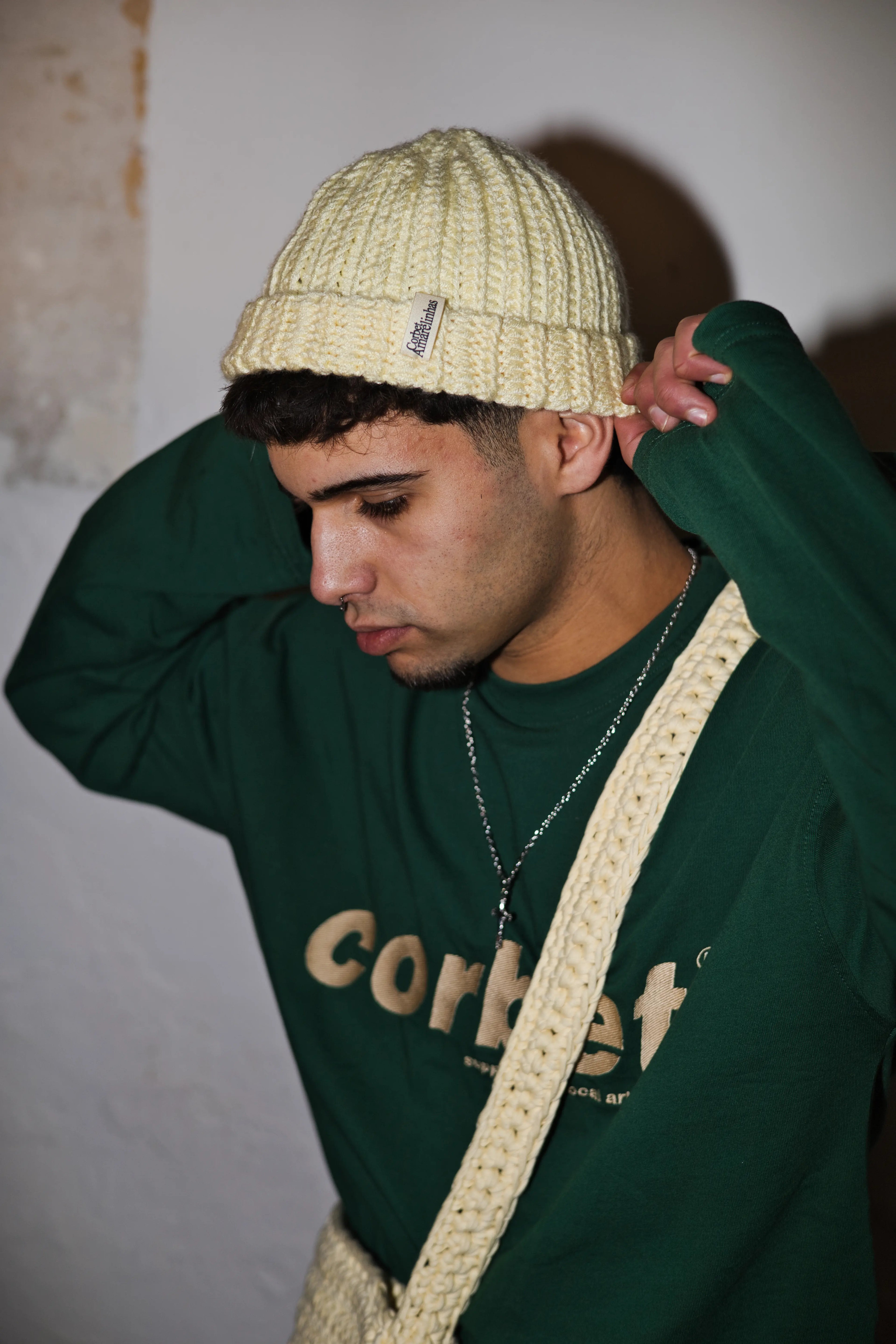 Person wearing a green long sleeve with 'corbet' embroidered logo and a handmade crochet beanie