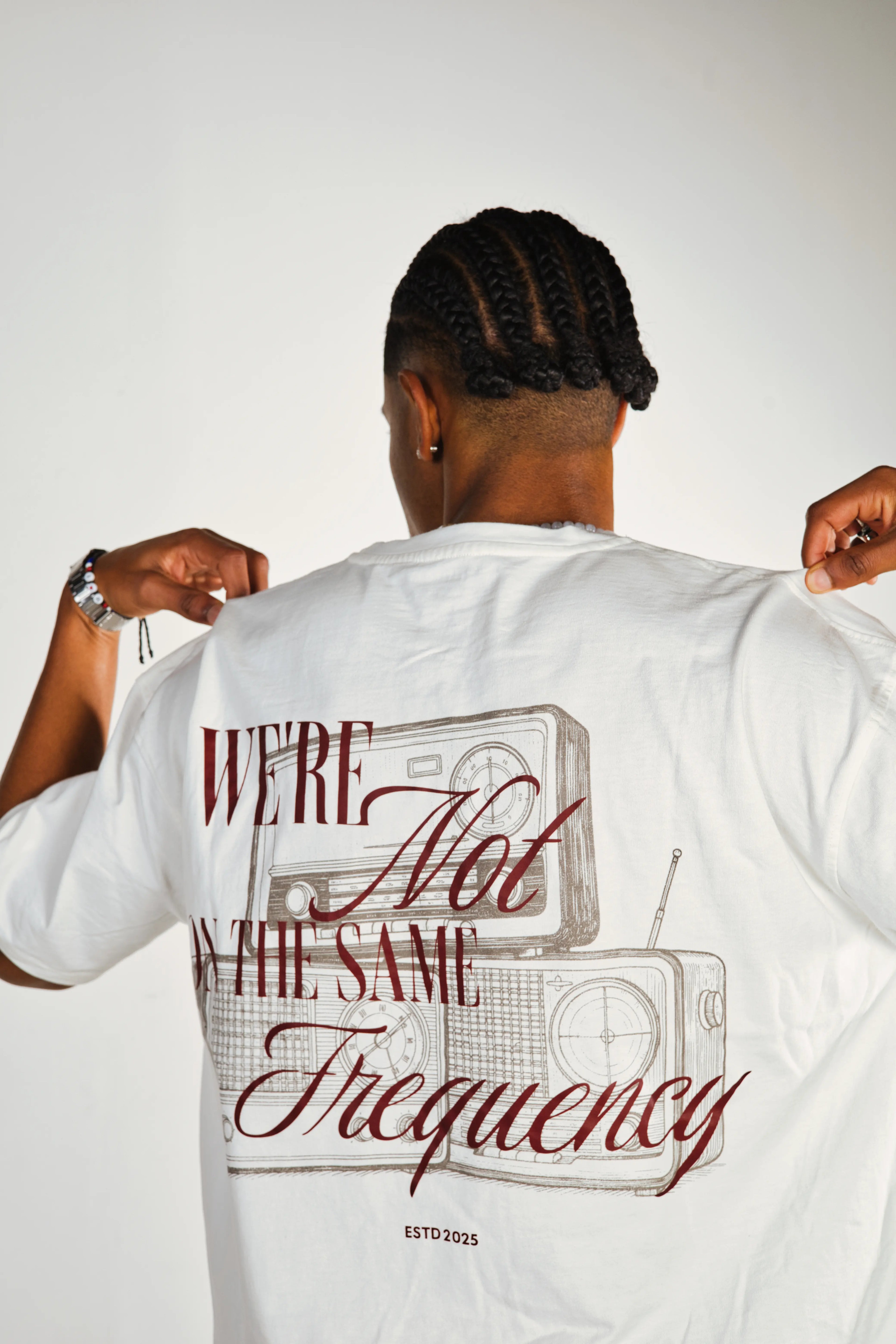 Person wearing a white t-shirt with a graphic and text on the back, standing against a plain background.