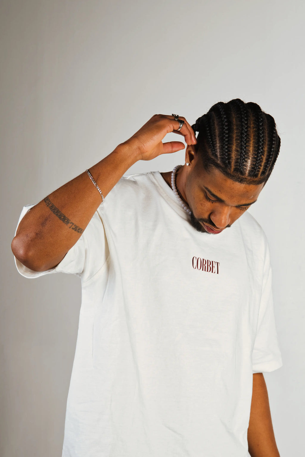 Person wearing a white t-shirt with text, adjusting hair against a plain background