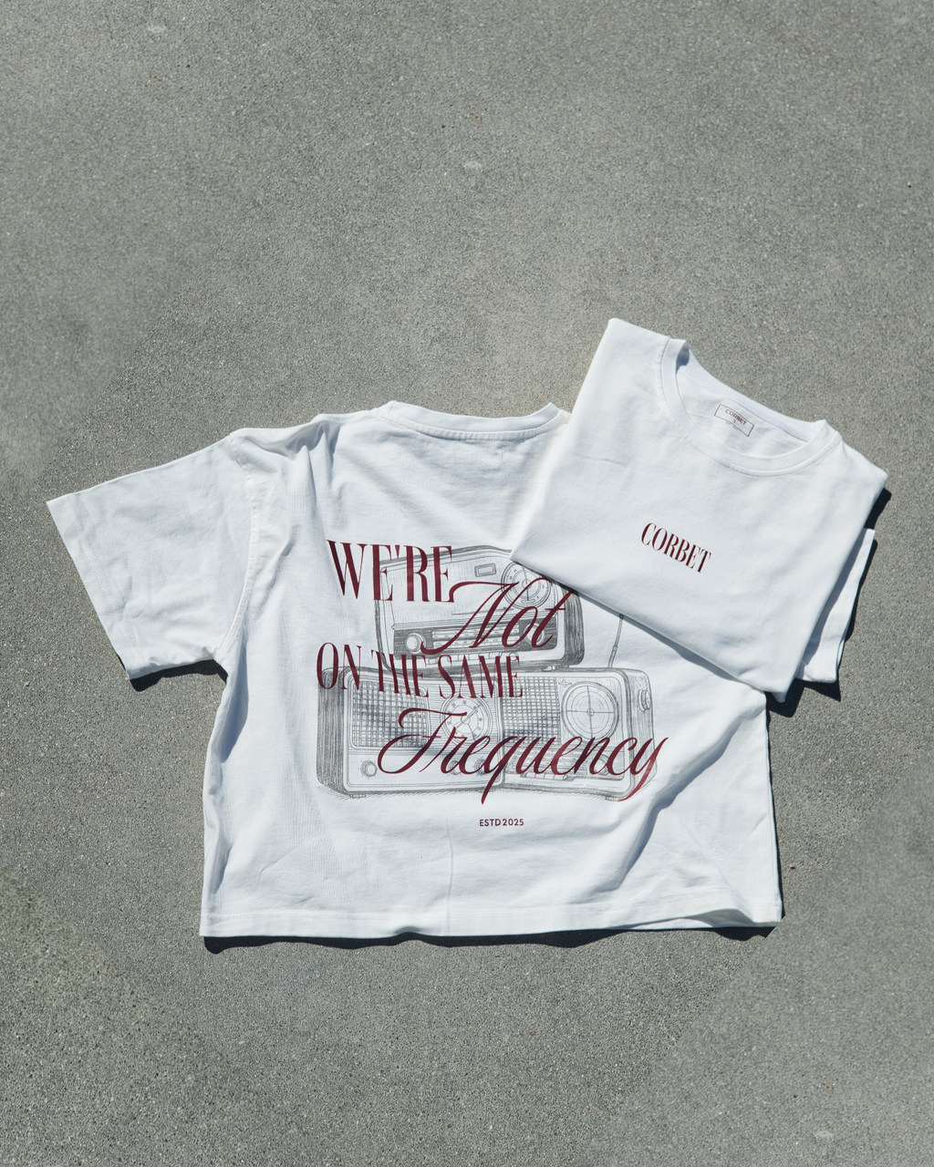 White t-shirt with red text and graphics on a gray surface