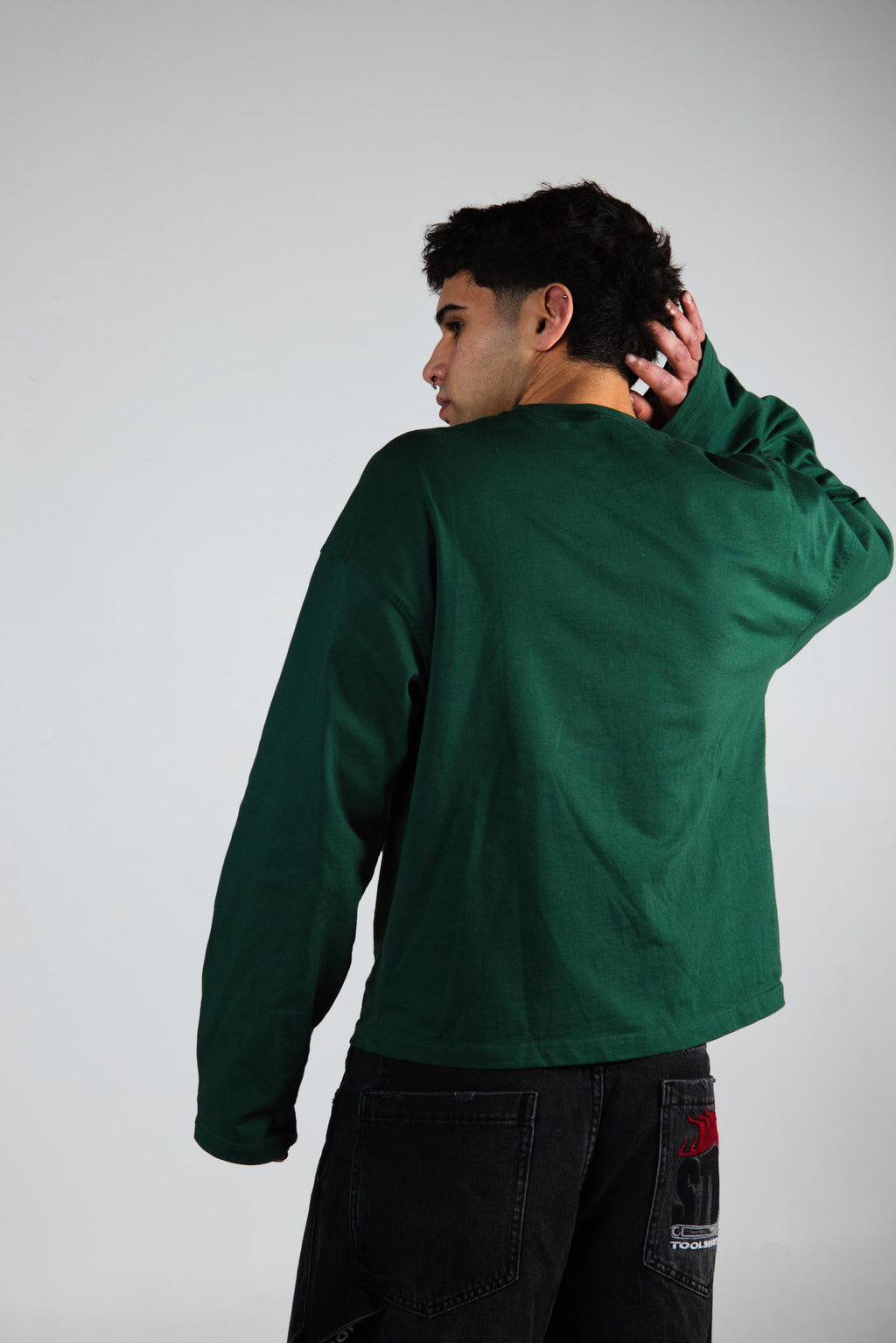 Person wearing a green long sleeve with a plain background