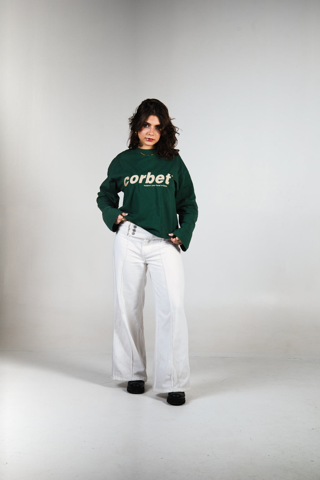 Person wearing a green long sleeve with 'corbet' logo on a white background