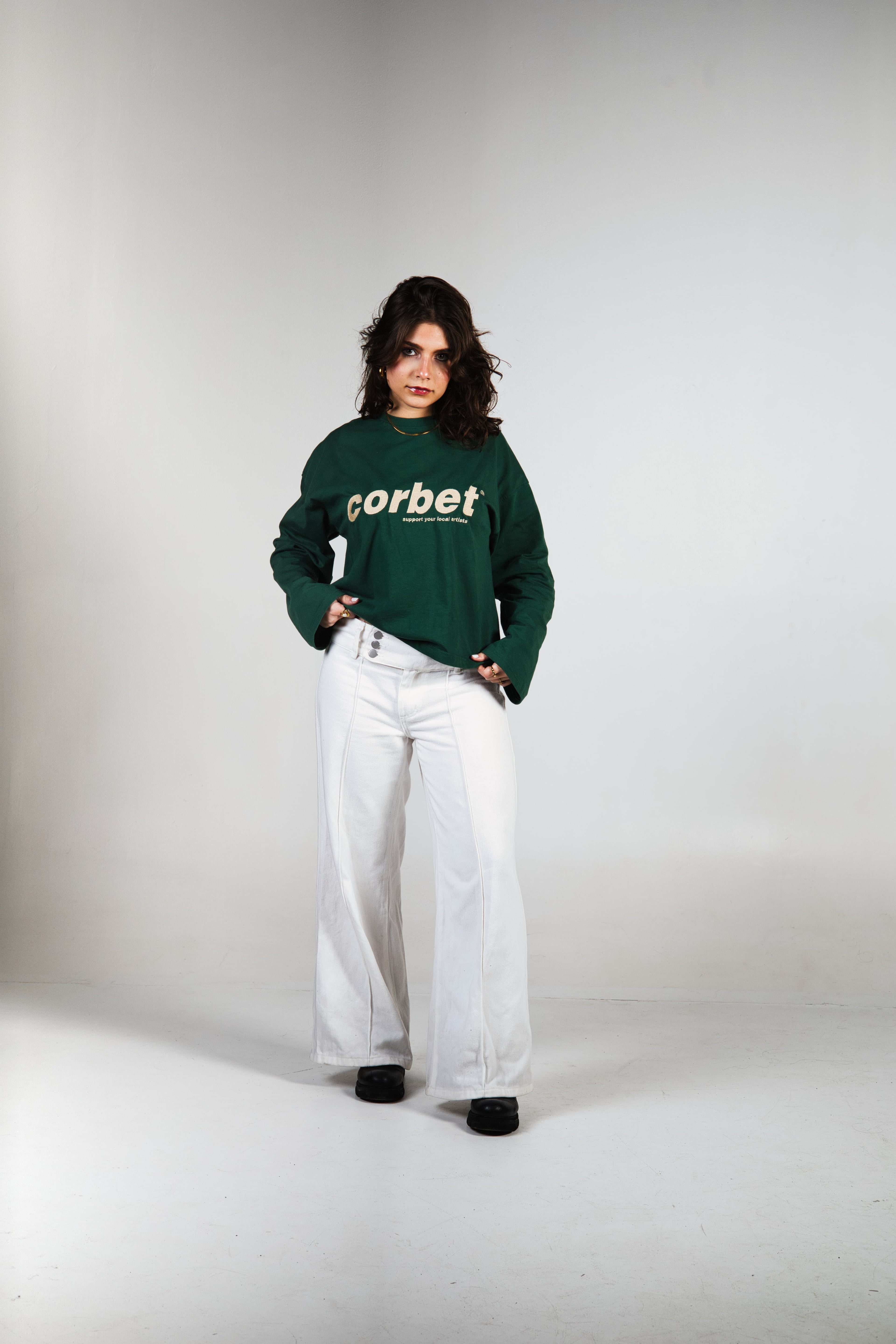 Person wearing a green long sleeve with 'corbet' logo on a white background