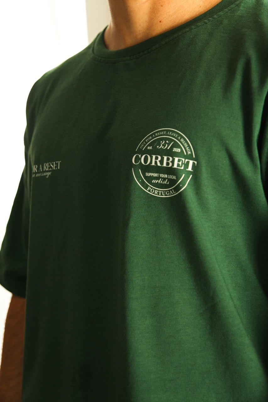 Green t-shirt with a logo and text on a plain background