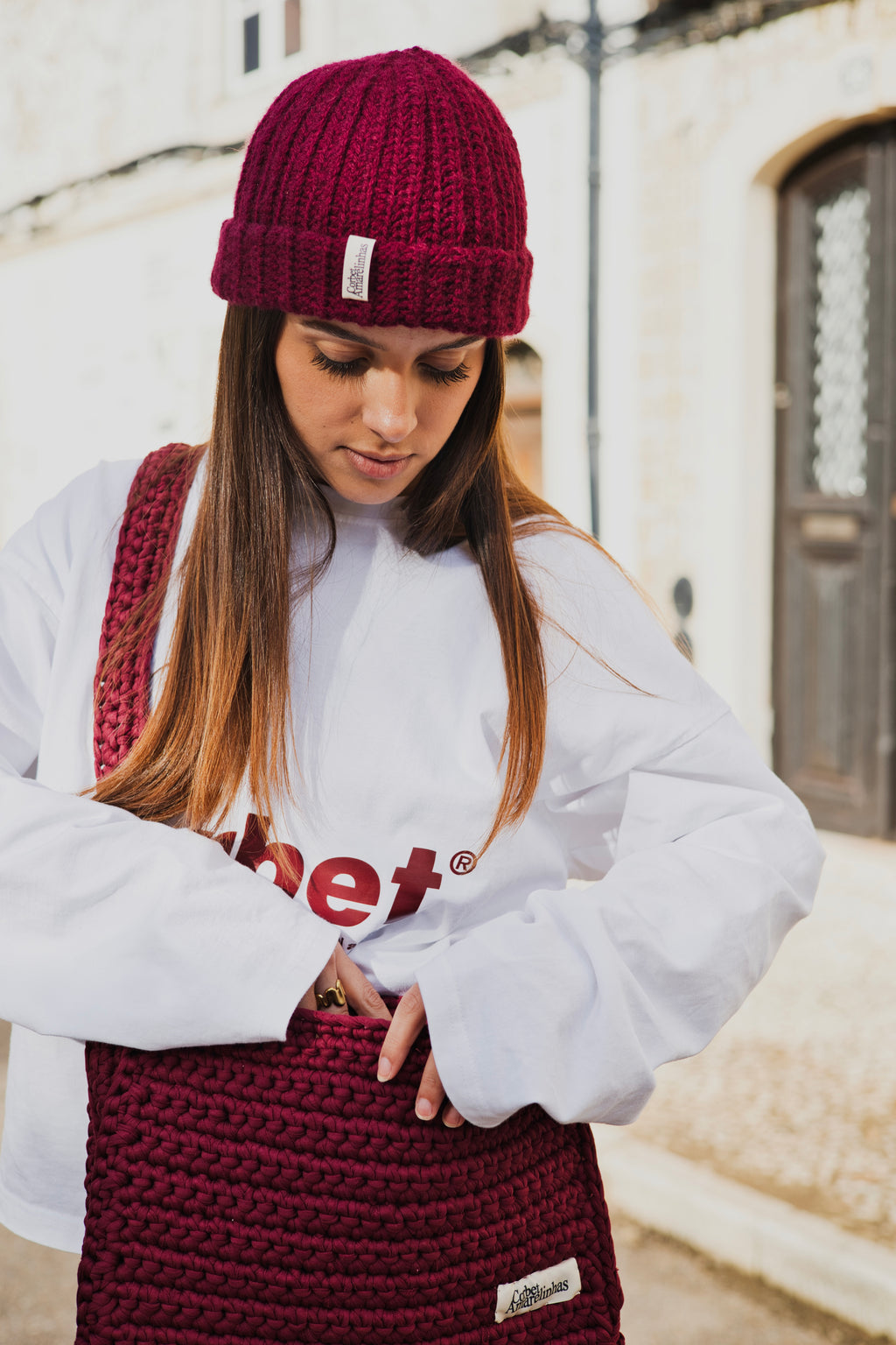 Isabel Aires wearing a Corbet white long sleeve with red text, handmade crochet beanie, and matching handmade crochet bag.