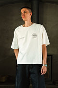 Person wearing a white t-shirt with a logo in a dark indoor setting