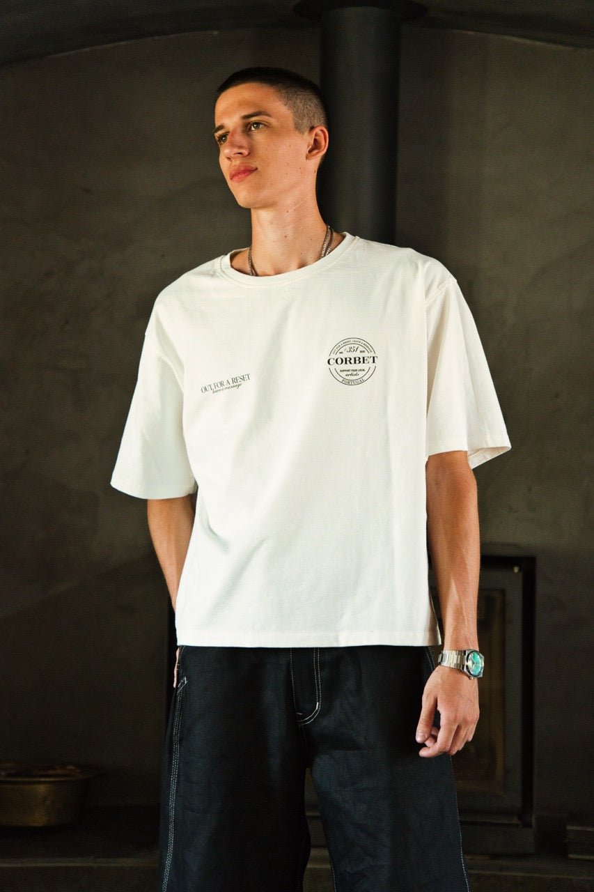 Person wearing a white t-shirt with a logo in a dark indoor setting