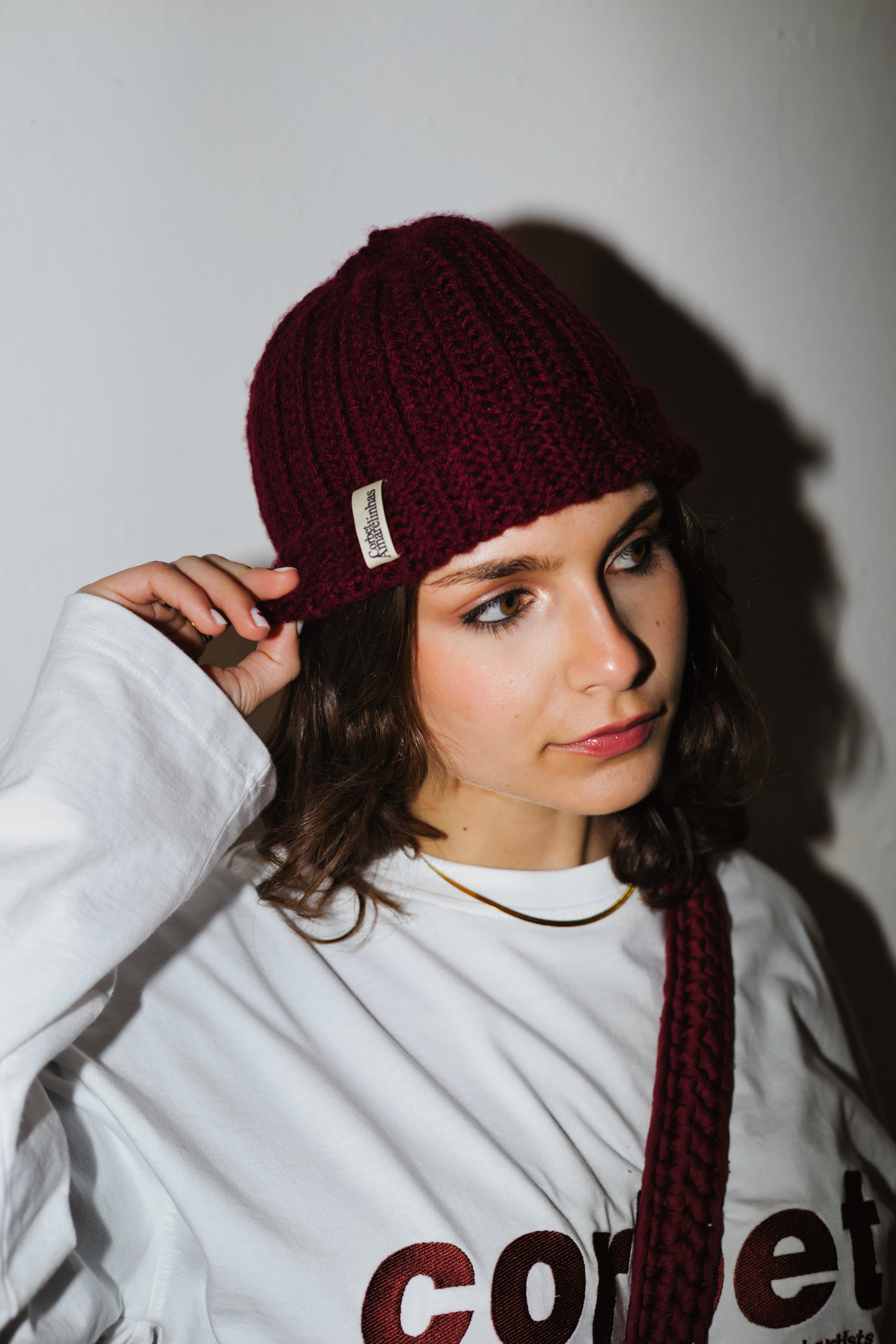 Girl wearing red wine crochet beanie with a matching longsleeve and crochet crossbody handmade bag